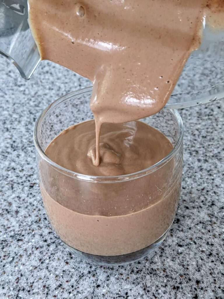 Creamy Chocolate Peanut Butter Smoothie being poured from a blender into a glass cup - The Simple Healthy Hub